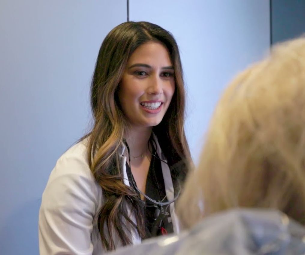 An image of Dr. Etesse in doctor clothing talking with a patient at her practice in Solana Beach